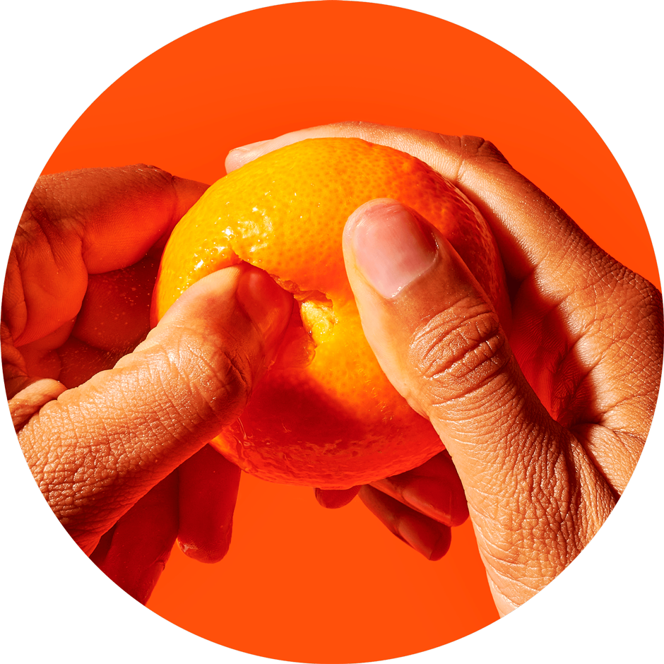 Two hands peeling a clementine on top of a bright orange backdrop